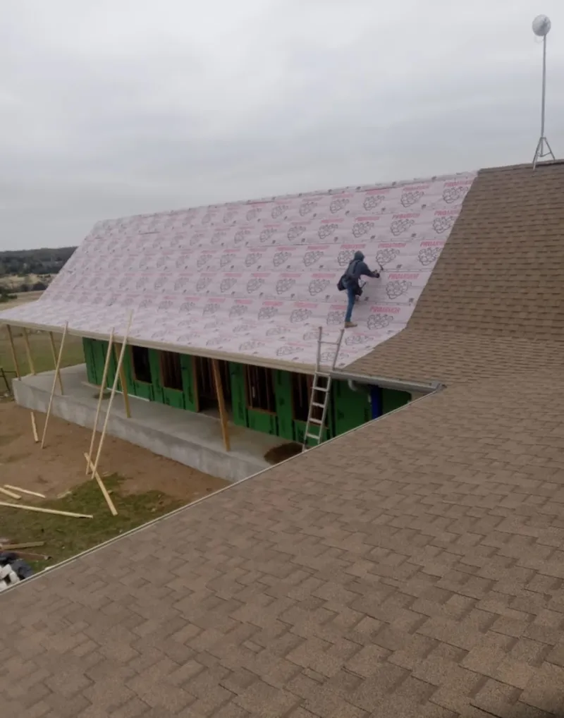 Worker preparing underlayment for a metal roof installation in Patterson